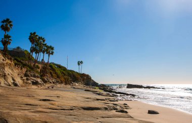 Bulutsuz bir günde San Clemente rıhtımının manzarası kayalık plajlar, yüksek palmiye ağaçları ve pahalı sahil manzaralı gayrimenkul.. 