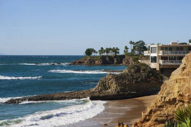 Bulutsuz bir günde San Clemente rıhtımının manzarası kayalık plajlar, yüksek palmiye ağaçları ve pahalı sahil manzaralı gayrimenkul.. 