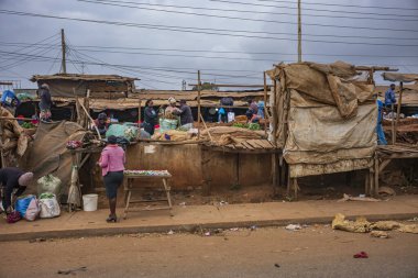 Nairobi, Kenya, - 17 Haziran 2025: Başkentte çalışan ve yaşayan insanların toprak yollarından görülen şehir hayatı. Seyirciler gıda pazarından sebze alıyorlar..