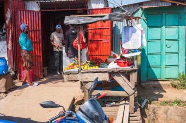 Migori, Kenya, - 17 Haziran 2025: Çalışan ve yaşayan insanların toprak yollarından görülen şehir hayatı. Yetişkinler büfede meyve ve sebze satıyor..
