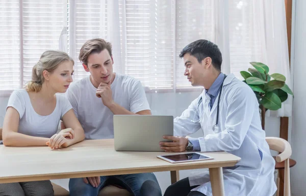 Caucasian couple patient husband and wife visit or meeting male doctor for pregnanct consultation at clinic or hospital. Lover meet medical advisor or physician for health treatment and medicare