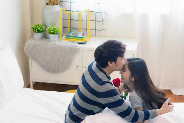 Güzel, çekici, genç Asyalı bir çift Rose 'u mutlu eder ve onu öper ve romantik bir anda gülümser. Aşıklar arası bağ ve ilişki. Karı koca aşk fotoğrafı konseptinde..