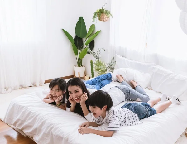Lovely happy Asian family at cozy home. Smiling mother, son and daughter enjoy ,relax and playful together in bedroom. Happiness relationship and bonding of love between parent and children moment