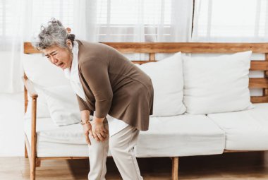 Evde tek başına diz ağrısı çeken Asyalı son sınıf öğrencisi bir kadın. Yaşlı kadın osteoporoz hastalığı ya da kas hasarı yüzünden acı çekiyor. Sağlık, tedavi ya da terapi konseptine sahip eski yetişkin hayat sigortası