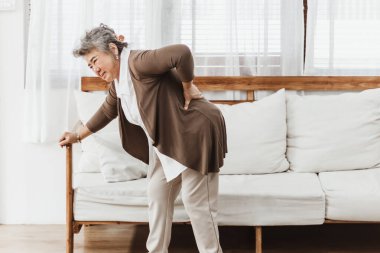 Evde yalnız başına sırt ağrısı çeken Asyalı son sınıf öğrencisi bir kadın. Yaşlı kadın osteoporoz ya da sırt yaralanması yüzünden acı çekiyor. Sağlık ve tedavi kavramına sahip eski yetişkin hayat sigortası