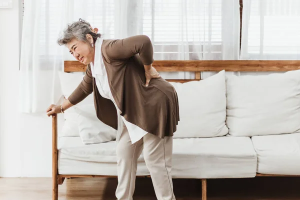 Evde yalnız başına sırt ağrısı çeken Asyalı son sınıf öğrencisi bir kadın. Yaşlı kadın osteoporoz ya da sırt yaralanması yüzünden acı çekiyor. Sağlık ve tedavi kavramına sahip eski yetişkin hayat sigortası