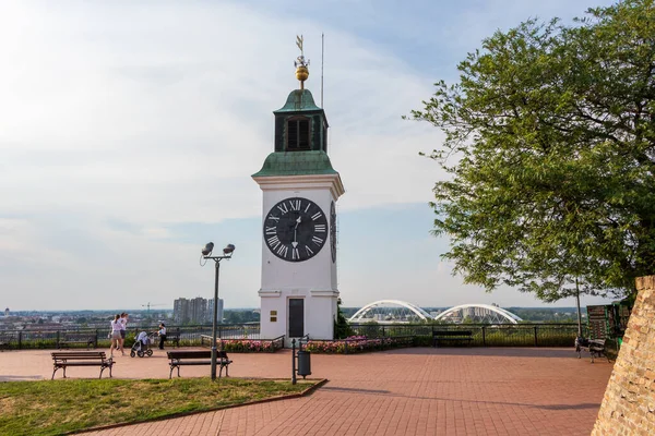 Novi Sad, Sırbistan - 9 Haziran 2021: Petrovaradin kalesindeki saat kulesi ve Sırbistan 'ın Novi Sad kentindeki Tuna Nehri üzerindeki Zezelj Köprüsü