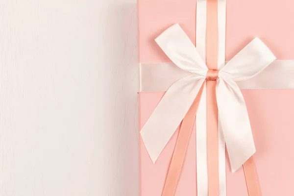 Pembe hediye kutusu İpek parlak fiyonk ve beyaz ahşap masa üzerinde kurdele