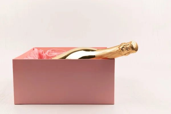 Золотая Бутылка Шампанского Лежит Подарке Розовая Коробка Белом Деревянном Фоне — стоковое фото