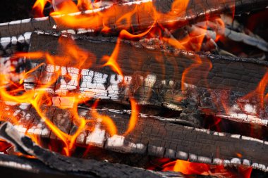 Açık havada kömürleri ve kırmızı alevleri olan şenlik ateşinde yanan odun yığınları.