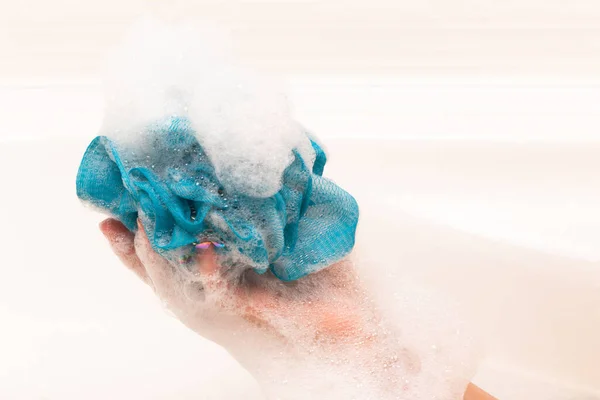 soap foam forms on a woman\'s hand in the bathroom, a stream of water. background light tile