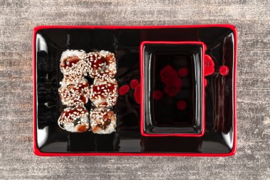 Yılan balığı ve susam tohumlu taze iştah açıcı börekler ve siyah tabakta soya sosu ve gri granit taşı.