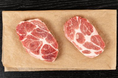 Masadaki kahverengi parşömen kağıdında taze çiğ domuz bifteği. Yukarıdan görünüm