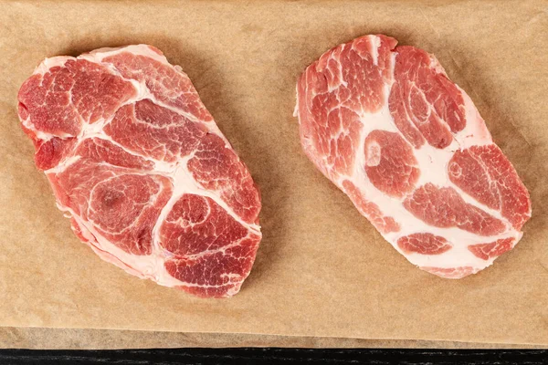 Verse Rauwe Gemarmerde Varkenssteak Bruin Perkamentpapier Tafel Zicht Van Bovenaf — Stockfoto