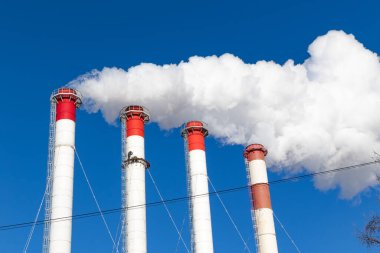 Kazan dairesinin kırmızı-beyaz bacaları, trafik ışığı ile donatılmış. Güneşli kış gününde mavi gökyüzüne karşı beyaz duman.