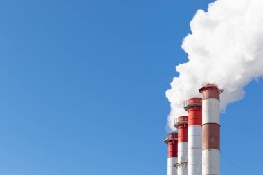 Kazan dairesinin kırmızı-beyaz bacaları, trafik ışığı ile donatılmış. Güneşli kış gününde mavi gökyüzüne karşı beyaz duman.