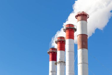 Kazan dairesinin kırmızı-beyaz bacaları, trafik ışığı ile donatılmış. Güneşli kış gününde mavi gökyüzüne karşı beyaz duman.