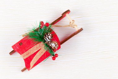 Noel Baba 'nın kırmızı kızağı köknar ağacı konileri ve yeşil ladin dallarıyla altın damarlı beyaz ahşap arka planda.