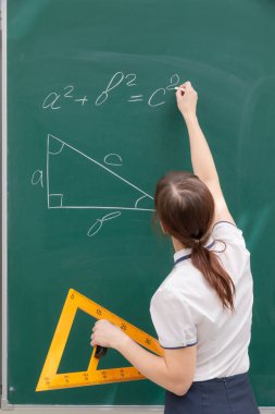 Tahtadaki sınıftaki öğretmen genç bayan cetvelle bir üçgen çiziyor. Portre. Kapat.
