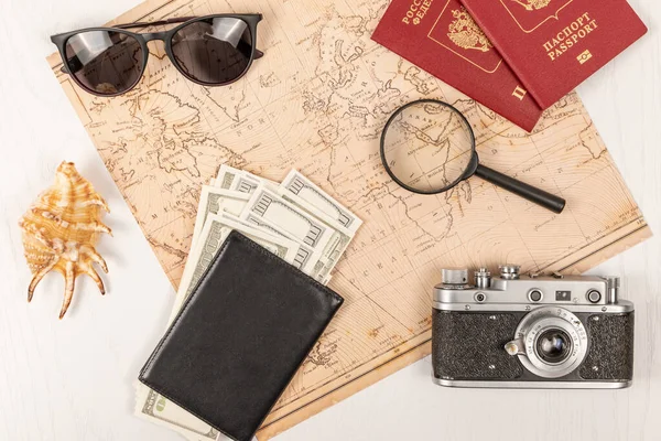 叶卡捷琳堡俄罗斯 世界地图 两张护照 一个放大镜 一个黑色皮夹里的钱 一个旧胶卷相机 太阳镜和一个白色木制桌子上的外壳 有选择的重点 护照俄罗斯联邦 — 图库照片