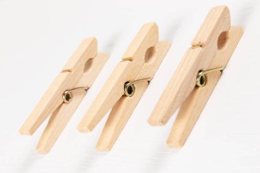 Beyaz ahşap bir masanın arka planında metal yay olan üç tahta mandal. Yakın plan. seçici odak