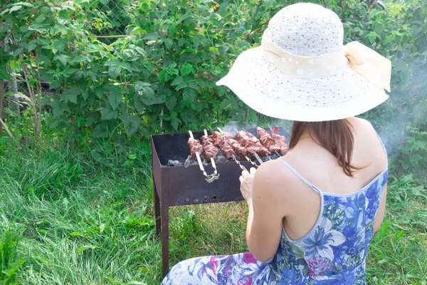 夏日里 一个戴着草帽的女孩在烤架上用绿叶做了香喷喷的鲜肉 后续行动 — 图库照片