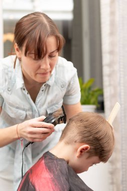 Genç anne kuaför karantina sırasında bebeğini saç makasıyla keser. Seçici odaklanma. portre