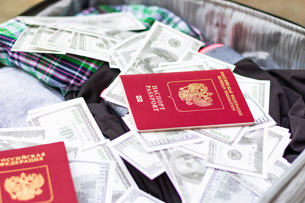 Two passports and a lot of money in a travel suitcase with things on a sunny summer day. Selective focus