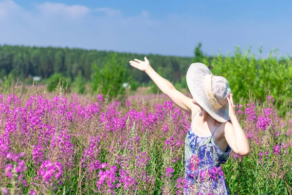 暑い夏の日に緑の森と青空を背景に 麦藁帽子の花の分野で若い女性 選択的焦点 — ストック写真