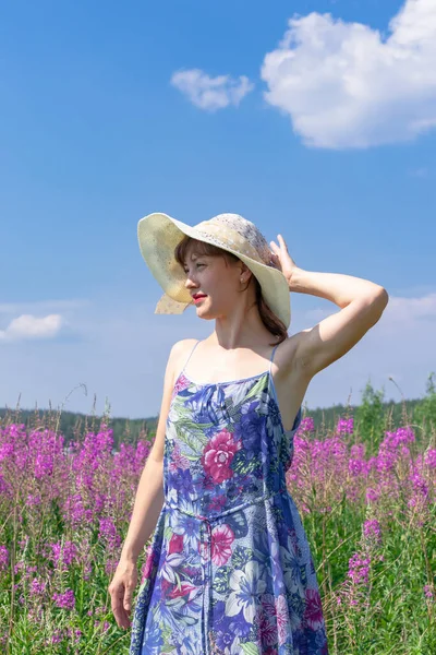 暑い夏の日に緑の森と青空を背景に 麦藁帽子の花の分野で若い女性 選択的焦点 — ストック写真