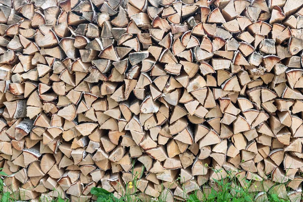 stacked woodpile of birch firewood in nature in the village on a bright summer day. Close-up