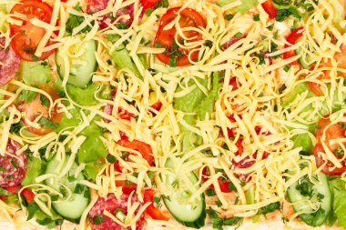 Shawarma için malzemeler ince bir pide ekmeğinin üzerine serilmiştir. Domates, yeşillik, salam, peynir, salatalık ve marul.