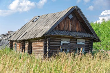 Eski ahşap kırsal, terk edilmiş bir evi beyaz bulutlu mavi bir gökyüzüne karşı güneşli bir yaz gününde harap etti. Yakın plan. Manzara
