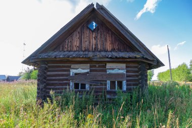 Eski ahşap kırsal, terk edilmiş bir evi beyaz bulutlu mavi bir gökyüzüne karşı güneşli bir yaz gününde harap etti. Yakın plan. Manzara