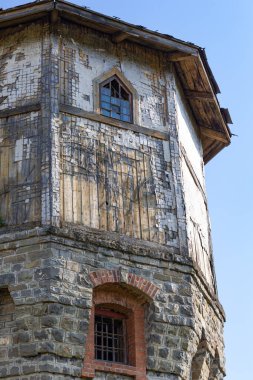Güneşli bir yaz gününde mavi gökyüzüne bakan taş bloklardan ve ahşap panellerden yapılmış antik bir gözetleme kulesinin üst kısmı. Yakın plan.