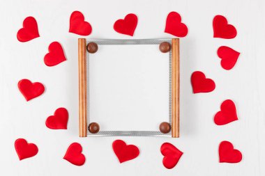 Ahşap arka planda dağınık kırmızı kalpli bir fotoğraf için ahşap çerçeve. düz yat