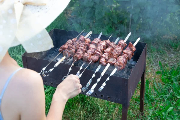 夏日里 一个戴着草帽的女孩在烤架上用绿叶做了香喷喷的鲜肉 后续行动 — 图库照片