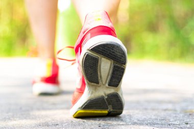 Güneşli bir yaz gününde parkta koşu yaparken parlak kırmızı spor ayakkabılı kadınların bacakları. Seçici odak