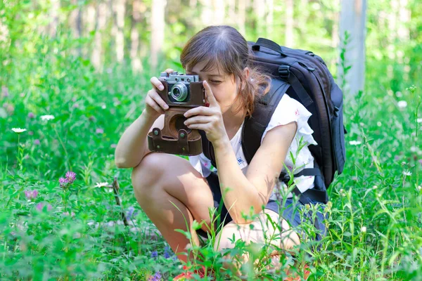夏天阳光明媚的日子里 年轻的女游客背着背包和照相机在森林里绿草的背景下游览 有选择的重点 — 图库照片