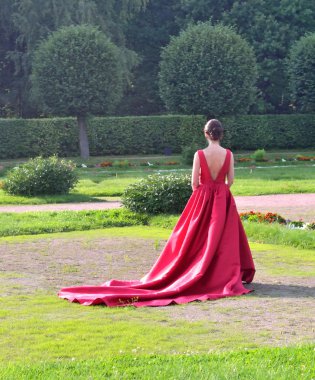 parkta ağaç kırmızı topu cüppe bekleyen bir kız