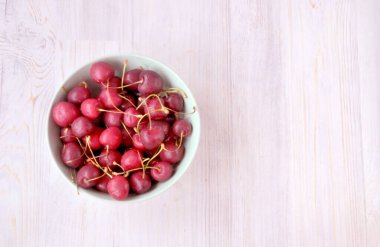 Kırmızı kirazlar ahşap bir sörfün üzerinde duran bir kaba dökülür.