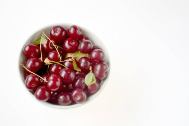 Beyaz arka planda izole edilmiş kirazlar bir bardağa doldurulur.