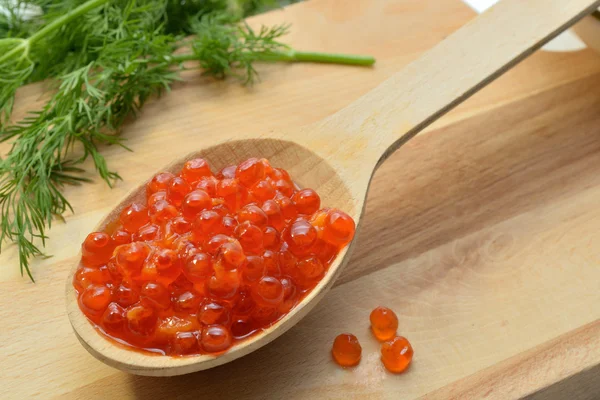 Red caviar in a wooden spoon and dill — Stock Photo, Image
