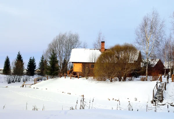Venkovská krajina s dřevěnými domy a zamrzlém rybníku — Stock fotografie