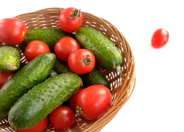 Pepinos e tomates em uma cesta de vime — Fotografia de Stock