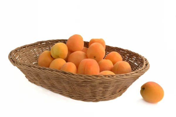 Frische Aprikosen sind in einem Weidenkorb isoliert auf weißem Hintergrund — Stockfoto