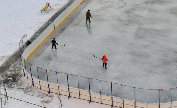 Barn spela hockey och skridskoåkning på rinken Royaltyfria Stockbilder