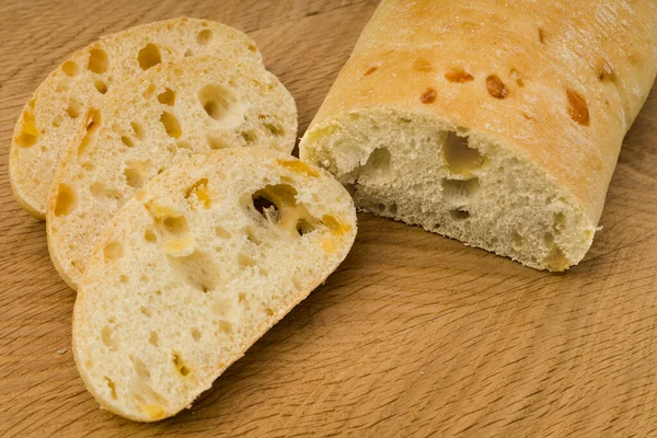Ciabatta - Italian bread with cheese cut into slices, on a wooden board