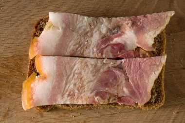 Tahta bir tahtanın üzerinde siyah ekmek ve tuzlanmış domuz yağı şeritli sandviç.