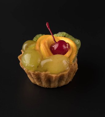 Kiraz üzümlü, kivili ve narenciyeli meyveli, siyah arka planda meyveli pasta.